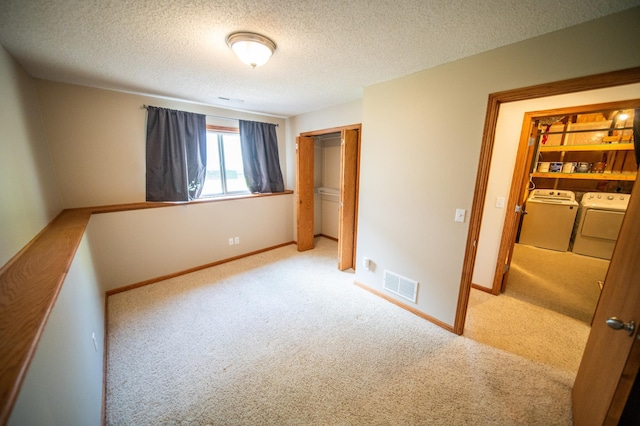 unfurnished bedroom featuring carpet, washer and clothes dryer, a textured ceiling, and visible vents