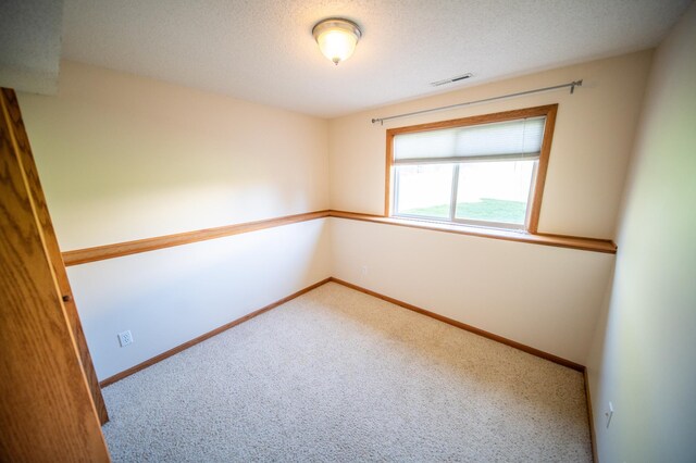 carpeted spare room with visible vents, a textured ceiling, and baseboards