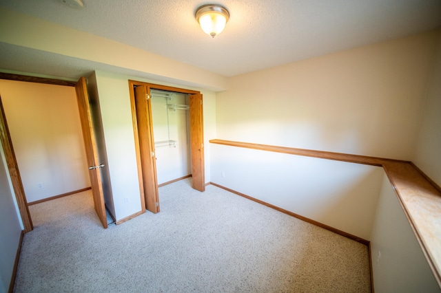 unfurnished bedroom with baseboards, a closet, and light carpet