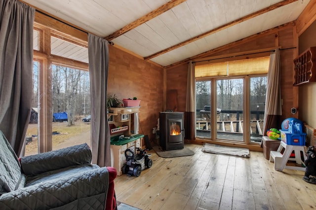 living room with a wood stove, hardwood / wood-style flooring, and vaulted ceiling with beams