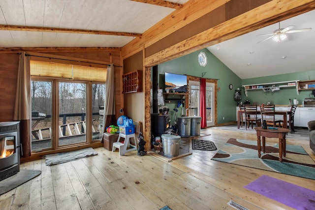 living room with a wood stove, vaulted ceiling with beams, and hardwood / wood-style flooring