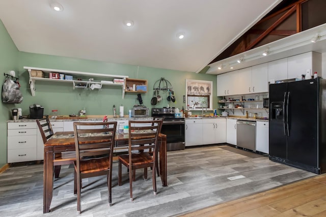 kitchen featuring light wood finished floors, stainless steel appliances, open shelves, vaulted ceiling, and white cabinetry