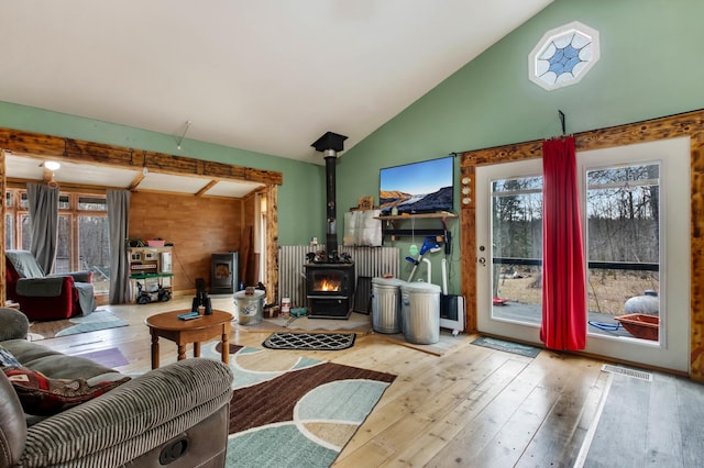 living room with visible vents, a wood stove, lofted ceiling, and hardwood / wood-style flooring