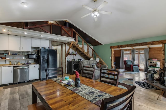 dining space featuring light wood-type flooring, a ceiling fan, stairway, vaulted ceiling, and washing machine and dryer