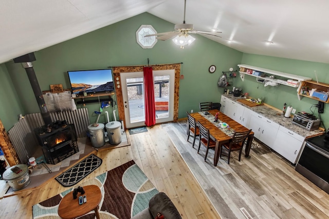 kitchen with lofted ceiling, a wood stove, light wood finished floors, and plenty of natural light