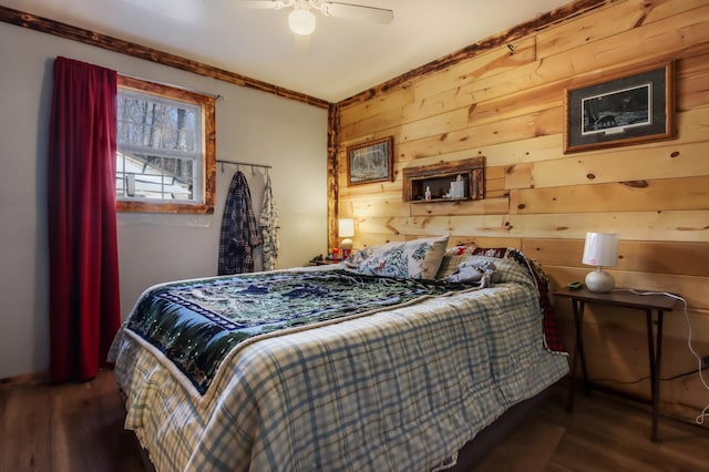 bedroom featuring crown molding, wood finished floors, wooden walls, and ceiling fan