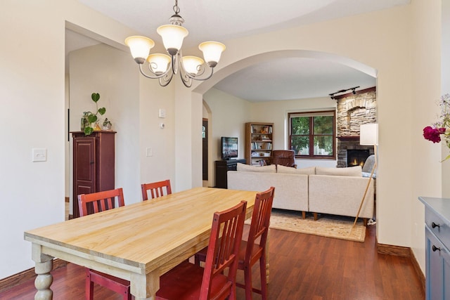 1584 Merrill St, Saint Paul, MN 55108 - dining space with arched walkways, a chandelier, dark wood-type flooring, and a fireplace
