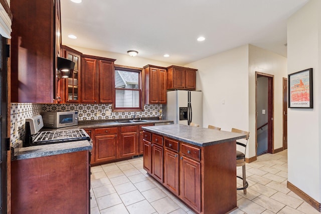 1584 Merrill St, Saint Paul, MN 55108 - kitchen featuring refrigerator with ice dispenser, dark countertops, tasteful backsplash, a kitchen breakfast bar, and light tile patterned floors