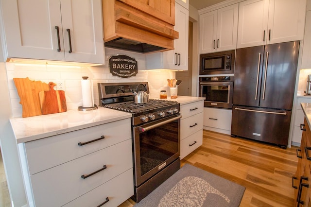 8825 Meadowlark Pkwy, Horace, ND 58047 - kitchen with custom exhaust hood, light wood-type flooring, white cabinetry, backsplash, and appliances with stainless steel finishes
