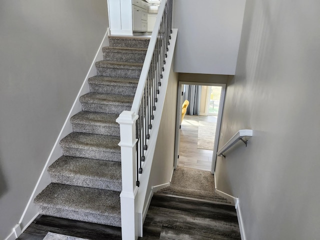 staircase with baseboards and wood finished floors