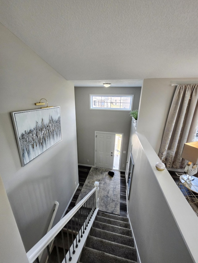 stairway featuring baseboards and a textured ceiling