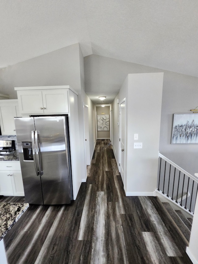 kitchen with white cabinets, vaulted ceiling, stainless steel fridge, and dark wood-type flooring