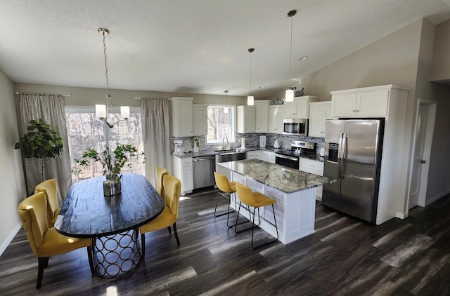 kitchen featuring a notable chandelier, appliances with stainless steel finishes, decorative backsplash, and dark wood finished floors