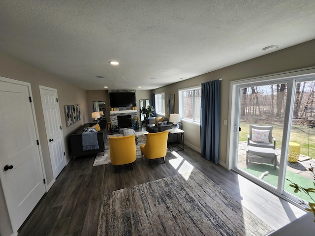 interior space featuring a fireplace, a textured ceiling, recessed lighting, baseboards, and wood finished floors