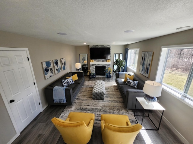 living area with a textured ceiling, a fireplace, wood finished floors, baseboards, and recessed lighting