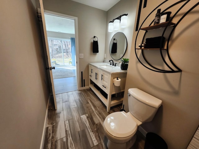 half bath with vanity, baseboards, toilet, and wood finished floors