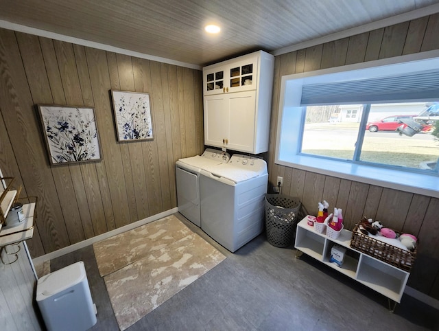 washroom featuring cabinet space, wooden walls, baseboards, and washer and dryer