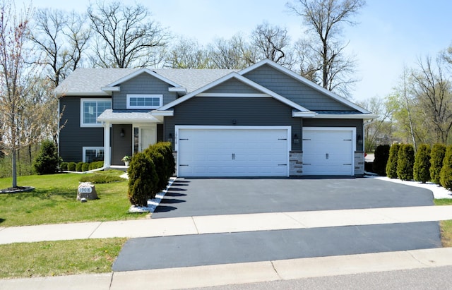 view of front of home featuring an attached garage, a shingled roof, a front yard, and aphalt driveway