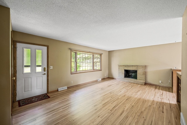 2235 Chestnut Rd, Medina, MN 55340 - unfurnished living room featuring wood finished floors, a brick fireplace, a textured ceiling, and baseboards