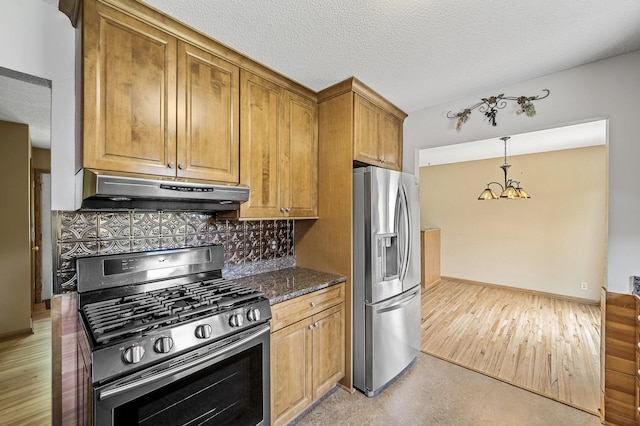 2235 Chestnut Rd, Medina, MN 55340 - kitchen with stainless steel appliances, under cabinet range hood, a chandelier, brown cabinets, and decorative backsplash