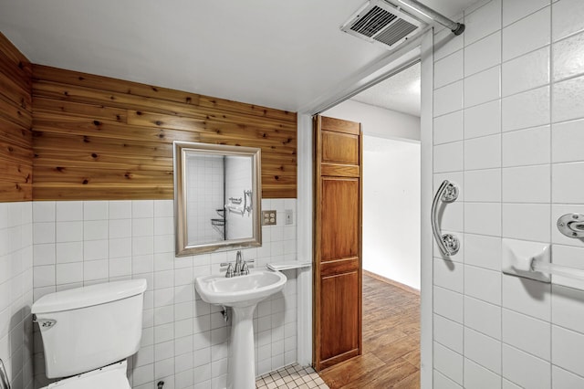 2235 Chestnut Rd, Medina, MN 55340 - bathroom featuring tile walls, toilet, wood finished floors, and a sink