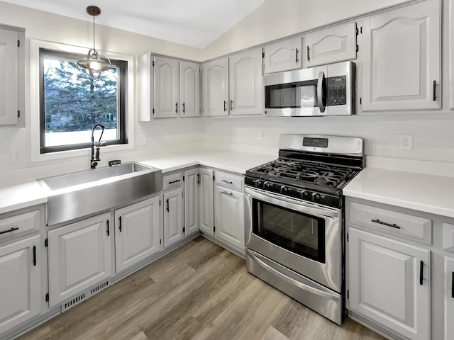 7426 Chesham Ln, Woodbury, MN 55125 - kitchen featuring light countertops, a sink, lofted ceiling, stainless steel appliances, and light wood finished floors