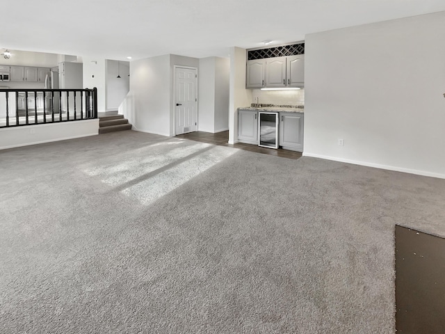7426 Chesham Ln, Woodbury, MN 55125 - unfurnished living room featuring wine cooler, baseboards, stairway, and carpet flooring