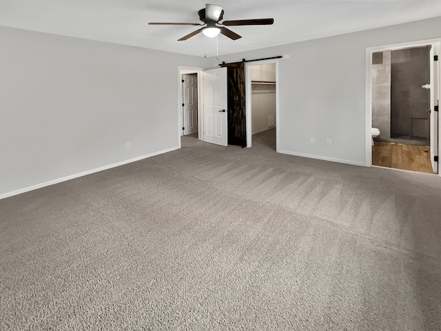 7426 Chesham Ln, Woodbury, MN 55125 - unfurnished bedroom featuring a closet, baseboards, a barn door, carpet floors, and a walk in closet