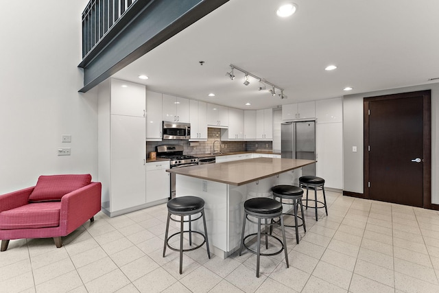 kitchen featuring a kitchen island, a kitchen breakfast bar, white cabinets, tasteful backsplash, and stainless steel appliances