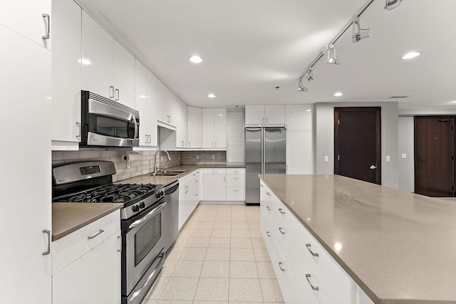 kitchen with appliances with stainless steel finishes, a sink, recessed lighting, white cabinetry, and backsplash