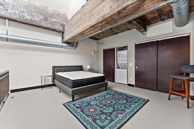 bedroom with visible vents, two closets, stacked washer / dryer, baseboards, and carpet flooring