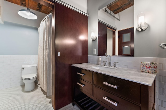 full bath featuring vanity, tile patterned flooring, toilet, tile walls, and a wainscoted wall