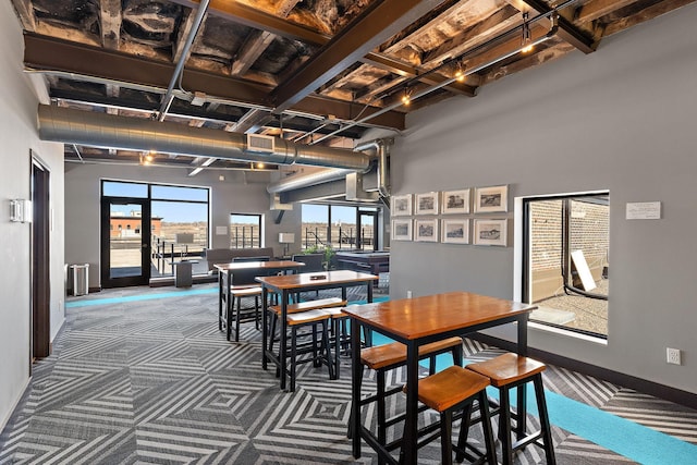 carpeted dining area with baseboards, visible vents, and a towering ceiling