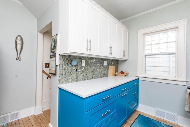 kitchen with tasteful backsplash, blue cabinetry, visible vents, and white cabinets