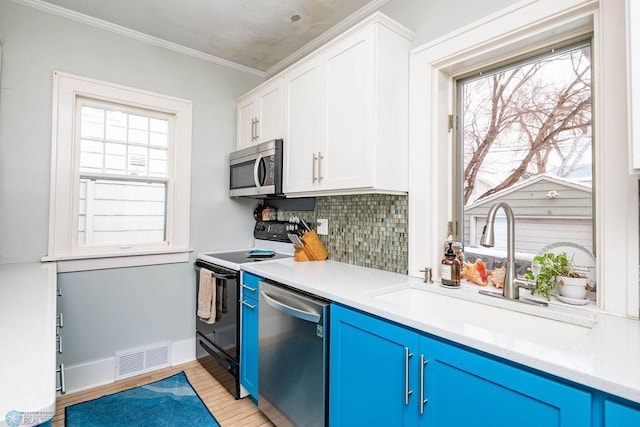 kitchen featuring blue cabinets, a sink, visible vents, stainless steel appliances, and tasteful backsplash