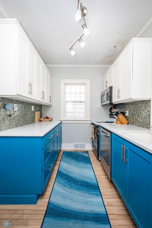 kitchen featuring appliances with stainless steel finishes, visible vents, blue cabinetry, and light wood-type flooring