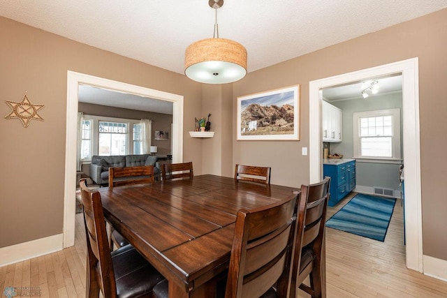 dining area with baseboards, visible vents, and light wood-style floors