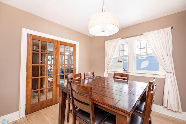 dining space featuring light wood finished floors and french doors