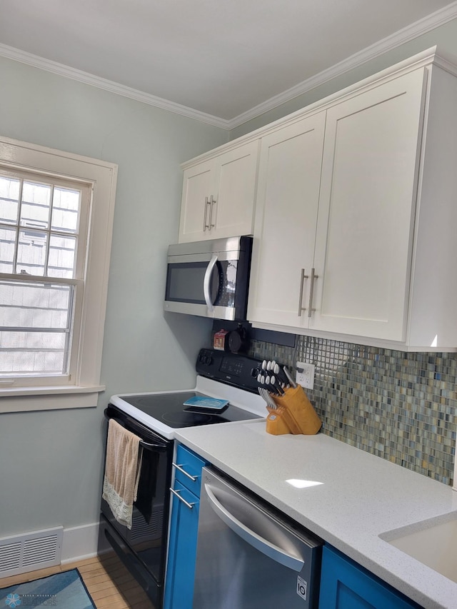 kitchen with appliances with stainless steel finishes, blue cabinets, tasteful backsplash, light countertops, and white cabinets