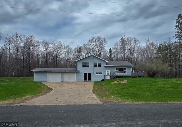 tri-level home featuring concrete driveway, a wooden deck, a front yard, and a garage