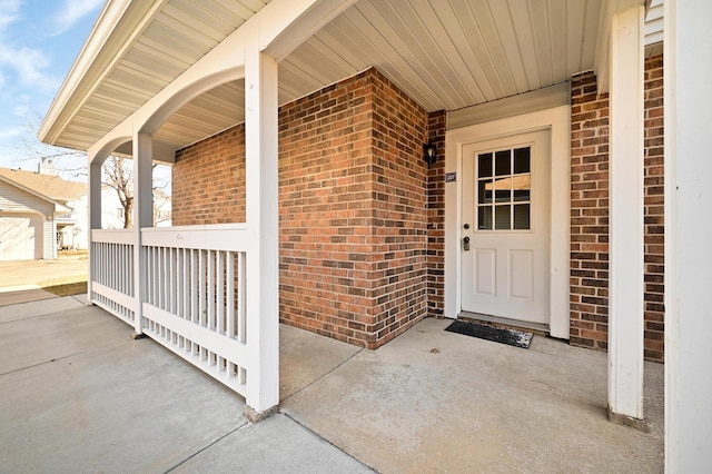 doorway to property with brick siding and a porch