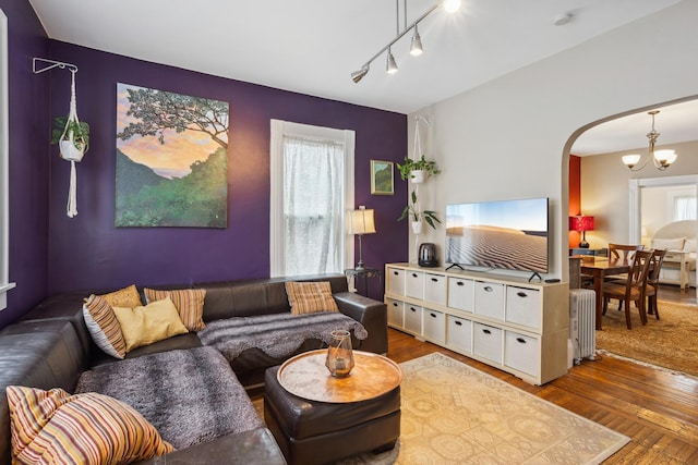 living area with arched walkways, radiator, a chandelier, and hardwood / wood-style flooring