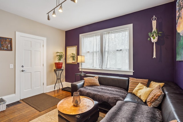 living room with wood finished floors, baseboards, and visible vents