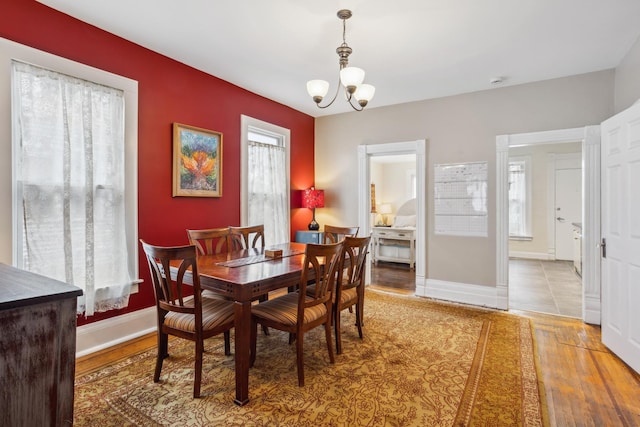 dining space featuring a chandelier, wood finished floors, baseboards, and a wealth of natural light