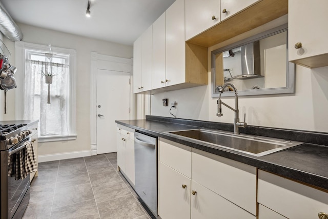 kitchen with stainless steel dishwasher, a sink, dark countertops, gas range oven, and baseboards