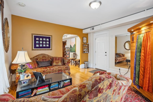 living room featuring visible vents, baseboards, arched walkways, and wood finished floors