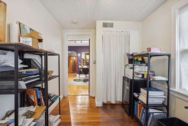 hallway with track lighting, visible vents, and wood finished floors
