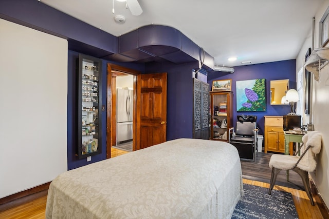 bedroom with visible vents, stainless steel refrigerator, and wood finished floors