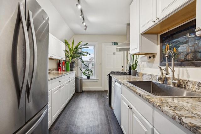kitchen featuring dark wood finished floors, wall chimney range hood, white cabinetry, a sink, and stainless steel appliances