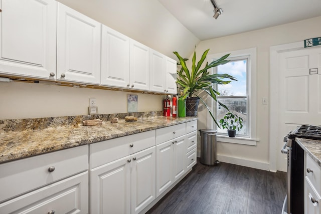 kitchen featuring dark wood-style flooring, stainless steel gas range oven, light stone counters, and white cabinetry